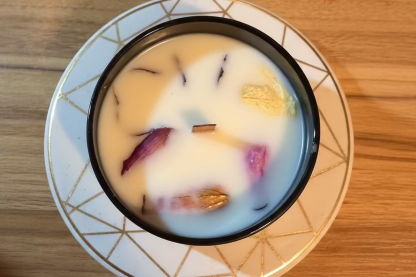 Candle with floral elements on a decorative plate on a wooden surface