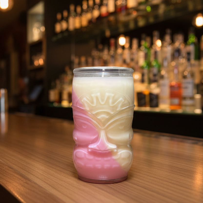 Pink and white tiki mug on a bar counter with a blurred bar background